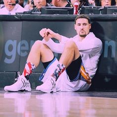 a man sitting on the floor in front of a crowd at a basketball game with his feet up