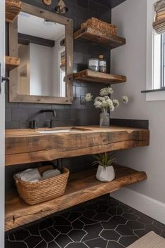 a bathroom with black tile and wooden shelves on the wall, along with a white sink