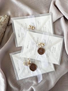 two envelopes with buttons on them sitting next to a rock and some fabric material