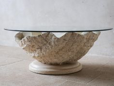 a glass and stone table with an unusual design on the top, in front of a white wall