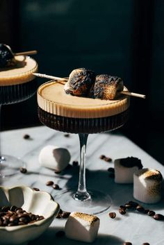 two desserts with chocolate and marshmallow toppings on a table