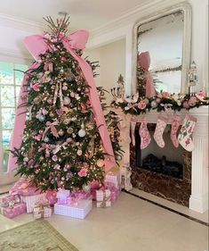 a decorated christmas tree with pink bows and stockings