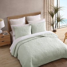 a bed in a bedroom with a green comforter and pillows