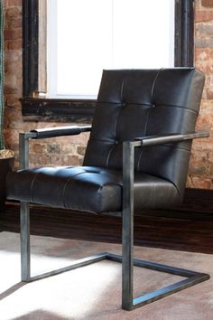 a black leather chair in front of a brick wall