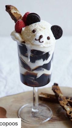 an ice cream sundae with chocolate and raspberries in a glass on a wooden tray