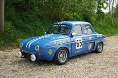 an old race car is parked on the gravel