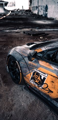 an orange and black sports car parked in a parking lot with graffiti on it's side