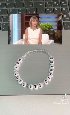 a woman sitting in front of a laptop computer with a beaded bracelet on it