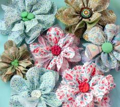 several different types of fabric flowers on a blue plate with green and red buttons in the center