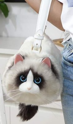 a white and black cat purse with blue eyes