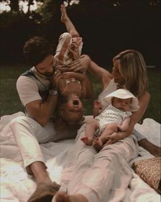 a group of people sitting on top of a blanket with a baby in the middle