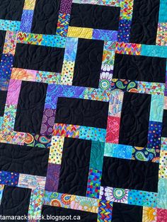 a quilt made with black fabric and colorful squares