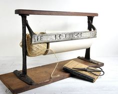 an old fashioned sewing machine sitting on top of a wooden stand next to a spool of thread