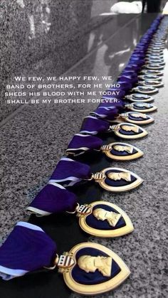 a row of medals sitting on top of a counter next to an inscription that reads we few, happy few, we band of brothers for he who shields his blood with me today shall be my brother forever