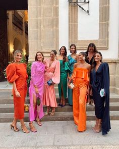 several women in different colored outfits posing for a photo on the steps of a building