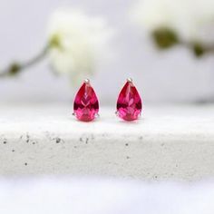 A pair of minimalistic sterling silver July birthstone stud earrings with pink ruby cubic zirconia gemstones make the perfect gift for wearers of all ages. Not to be found anywhere on the high street, our beautiful July birthstone studs are crafted from the finest sterling silver. Featuring gorgeous teardrop-shaped pink ruby cubic zirconia gemstones set in a beautiful silver claw setting, these dainty silver birthstone stud earrings feature a classic butterfly and post fastening and are suitable for almost any age.  Make your earrings even more special by choosing one of our beautiful card inserts set inside the lid of a high-quality gift box. Add a name, date, initials, or short message to make a truly unique bespoke gift for them. We think this piece is a wonderfully thoughtful way to ma Sterling Silver Pink Birthstone Earrings, Pink Sterling Silver Birthstone Earrings, Pink Birthstone Earrings In Sterling Silver, Ruby Stud Earrings, Ruby Earrings Studs, Pink Ruby, Claw Setting, Bespoke Gifts, Cz Stud Earrings