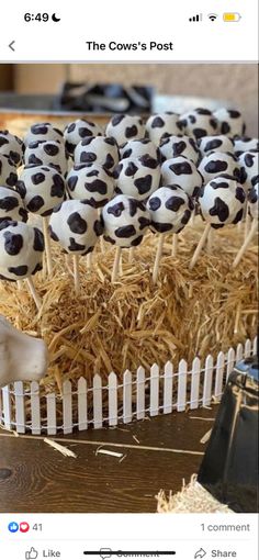 a table topped with cake pops covered in black and white soccer balls on top of straw