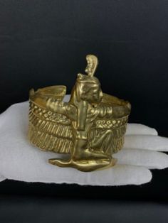 a gold ring sitting on top of a white napkin next to a black background with an angel