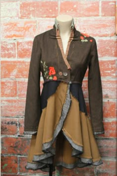 a mannequin wearing a jacket and skirt with flowers on the front, standing against a brick wall