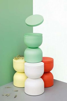 a stack of different colored vases sitting next to each other in front of a green wall