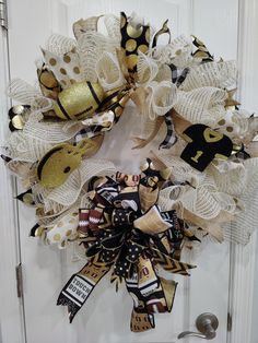 a football wreath with gold and black decorations hanging on a white front door or door