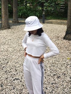 a woman in white outfit and hat standing on the ground with her hands on her hips