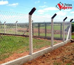 a fence that is next to a field with grass and dirt on the other side