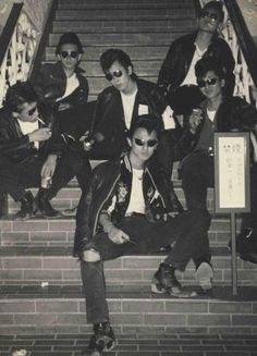 a group of young men sitting on top of stairs next to each other in black and white