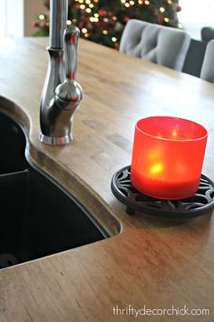 a lit candle sitting on top of a kitchen counter next to a sink and faucet