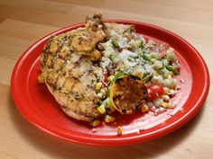 a red plate topped with chicken and vegetables