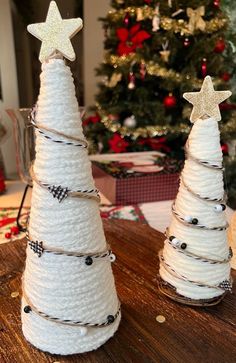 two white christmas trees made out of twine on a wooden table next to a christmas tree