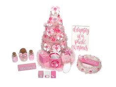 a pink christmas tree with baby's booties and other items around it on a white background