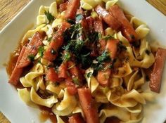 a white plate topped with pasta and meat covered in sauce