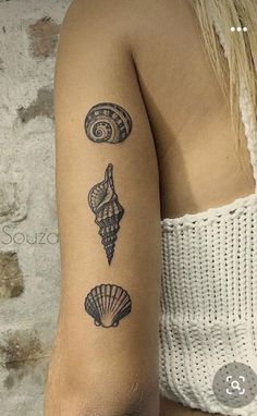 a woman's arm with three seashells tattooed on the back of her left arm