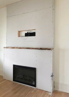 an empty room with a fire place in the middle and a wall mounted tv above it