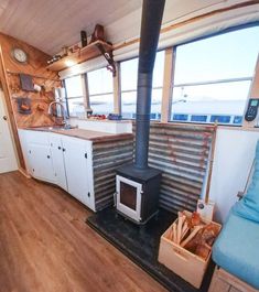 a stove in the middle of a kitchen with wooden flooring and cabinets on either side