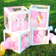 pink and white baby blocks with balloons on the grass