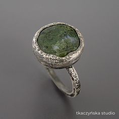 "Green Lake, Moss Agate Statement Ring, Unique Edgy Round Green Gem Ring, Contemporary Art to Wear Rough Ring, Unique Gemstone Huge Raw Ring Raw textured ring with one-of-a-kind Moss Agate ring. Black patinated and brushed.  Rustical organic style design. The ring in the photos is size: Europe 16, France 56, Great Britain P, USA 7 ½, Germany 17 ¾, Japan 15 It can be enlarged to size: Europe 18, France 58, Great Britain R, USA 18 ¼, Germany 18, Japan 16. Other sizes are made to order. The available stone is shown in the last photo. The ring can be custom-made in any size, also with a different stone. Due to the fact that each piece is made by hand with a unique stone, it can slightly vary from the one in the photos. Each movement of a hand holding a torch, and each blow of a hammer is a bit Green Gem Ring, Rough Ring, Raw Ring, Statement Rings Unique, Green Gem, Smoky Quartz Ring, Moss Agate Ring, Green Lake, Contemporary Ring