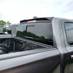 the back end of a pick up truck parked in a lot with other trucks behind it