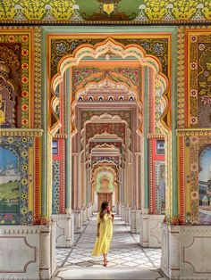 a woman in a yellow dress is walking through an ornate building with colorful walls and arches