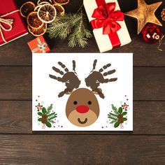 a christmas card with a reindeer's handprint on it and presents around it