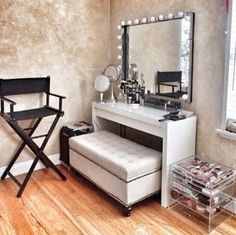 a room with a vanity, chair and mirror on the wall next to a window