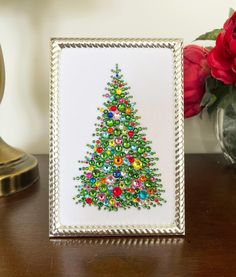 a decorated christmas tree in a frame on a table next to a vase with flowers