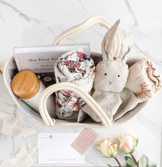 a basket filled with various items on top of a white marble counter next to flowers