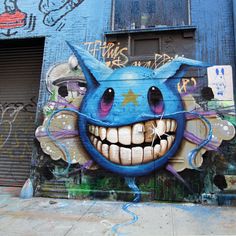 graffiti on the side of a building with an evil face and teeth painted on it