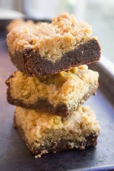 three brownies stacked on top of each other in front of a pan filled with cookies