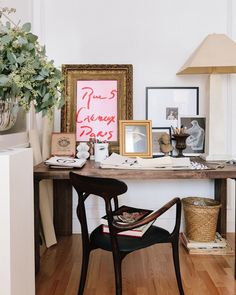 a wooden desk topped with pictures next to a lamp and potted plant on top of a hard wood floor