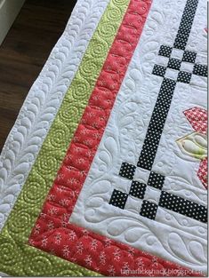 a close up of a quilt on a bed with a wooden floor in the background