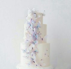 a three tiered white wedding cake with butterflies on it