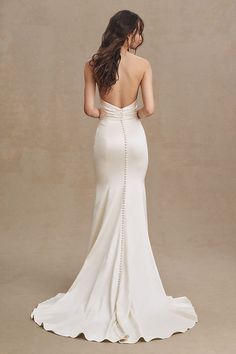 the back of a woman in a white wedding dress, with her hands on her hips